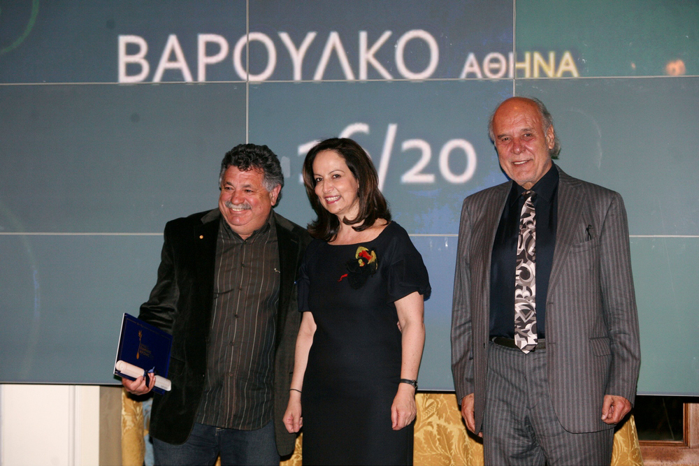 Πανευτυχής ο Λευτέρης Λαζάρου που μόλις έχει παραλάβει το βραβείο για το καλύτερο εστιατόριο Ελληνικής Κουζίνας από την υπουργό Άννα Διαμαντοπούλου. Δεξιά ο Διονύσης Κούκης (2012)