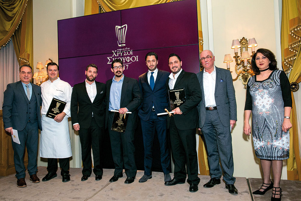 Τα βραβεία για τα εστιατόρια της Αθήνας που συγκέντρωσαν βαθμολογία 15/20 κι έναν Χρυσό Σκούφο. Ο Αστέριος Κωστούδης, σεφ του «GB Roof Garden», ο Παναγιώτης Κρεμμύδας, συνιδιοκτήτης του «CTC», ο Αλέξανδρος Τσιοτίνης, συνιδιοκτήτης-σεφ του «CTC», ο Θοδωρής Αγιοστρατίτης και ο Παναγιώτης Γιακαλής, συνιδιοκτήτης και σεφ του «Patio» αντίστοιχα με την commercial manager της British Airways σε Ελλάδα, Κύπρο και Τουρκία Freddie Stier, που έκανε την απονομή, και τους παρουσιαστές της βραδιάς.